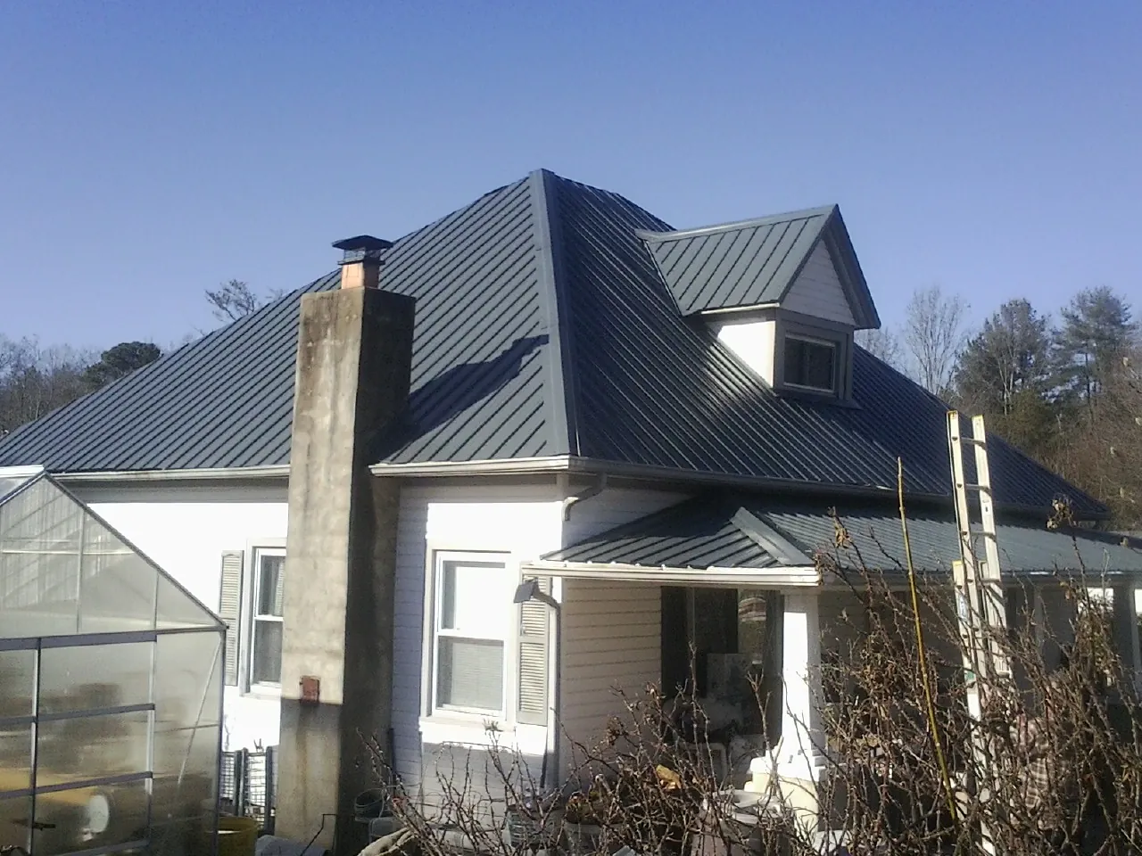 Dark blue standing seam metal roof on a white farmhouse with dormer — Slate & Tile Roof Repair by Roofing Brothers in Beech Grove